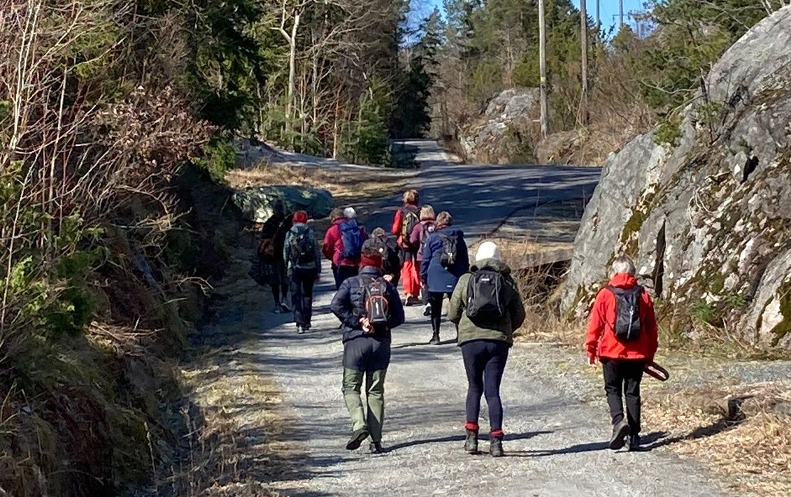Mennesker som går på tur på en grusvei i naturen.